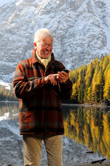 Uomo anziano scrive un messaggio con il telefono cellulare