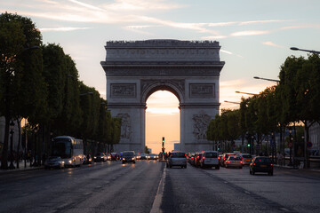 Motor traffic along the Champs-Elysees towards the famous landmark Arc dr Triomphe on a summer's evening in Paris, France.