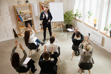 Male speaker giving presentation in hall at university workshop. Audience or conference hall. High angle view of unrecognized participants. Scientific, business conference event, training. Education