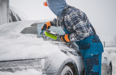 Men Removing Snow From His Vehicle and Deicing Windshield.