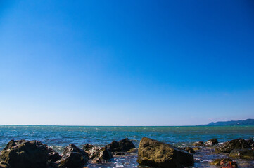 rocky sea shore with pebble beach, waves with foam