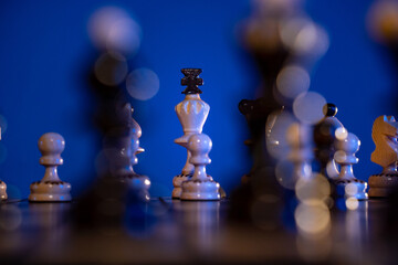 Chess board with chess pieces on blue background. Concept of business ideas and competition and strategy ideas. White king close up.