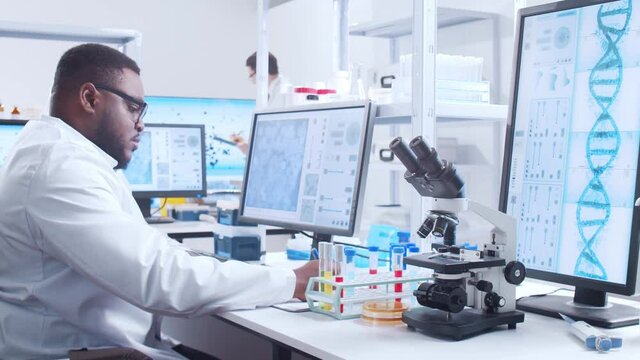 Professional African-American scientist is working on a vaccine in a modern scientific research laboratory. Genetic engineer workplace. Futuristic technology and science concept.