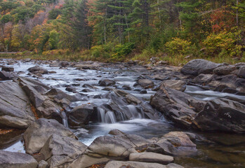 Water flows down the Black River in Vermont during peak fall color.