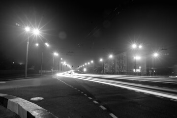 Cars drive at speed through the city at night.