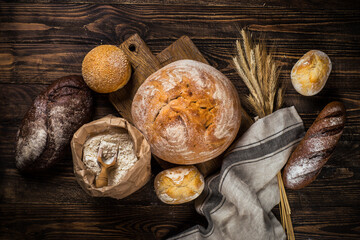 Fresh bread and buns at rustic wooden table. Top view image.