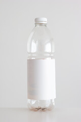 Clear empty plastic bottle with red lid and white empty label isolated on white vertical shot