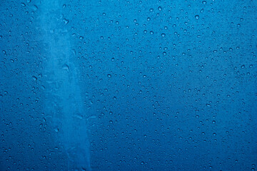 Rain water droplets accumulated on the surface of blue fabric umbrella close up detail shot