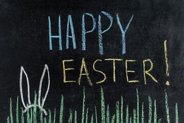 Fototapeta na wymiar Happy Easter on a chalk board, grass and Easter bunny ears.