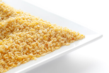 Crunchy Moong Dal in a white ceramic square plate, made with roasted Mung bean. Pile of Indian spicy snacks (Namkeen), under backlight, side view, against the white background.