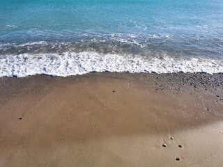 Fototapeta na wymiar Little waves and foamy on beautiful golden beach. Shore