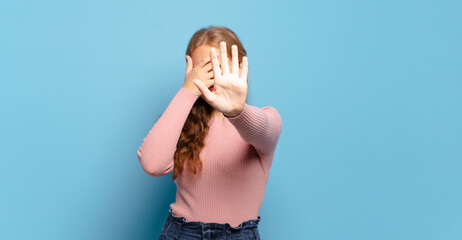 blonde pretty woman covering face with hand and putting other hand up front to stop camera,...