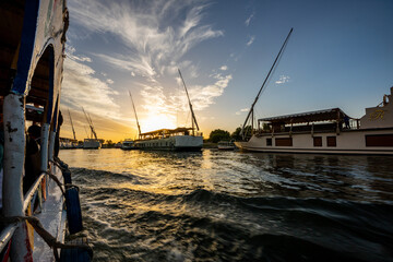 River trip over the Nile in Egypt with a beautiful bright colorful sunset with sparkling water and Nile ships