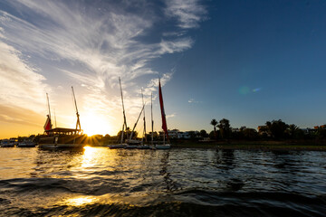 River trip over the Nile in Egypt with a beautiful bright colorful sunset with sparkling water and Nile ships