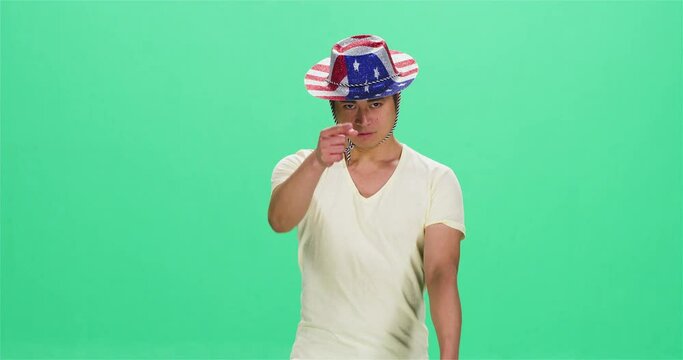 Man wearing American flag hat pretending to shoot, green screen