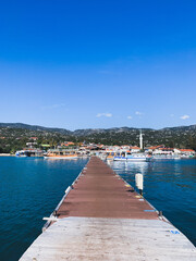 Fototapeta premium Waking pier in the blue sea, sea town view from the sea