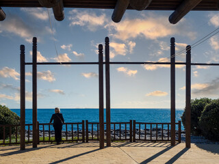 Mujer disfrutando del paisaje marino desde una pérgola de madera