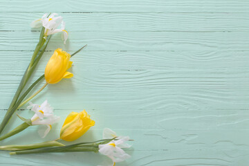 white irises and yellow tulips on green wooden background