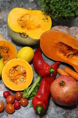 colorful vegetables, tomatoes, peppers, and large orange pumpkins cut in half, celery with fresh oregano and parsley in the background, healthy food, celery