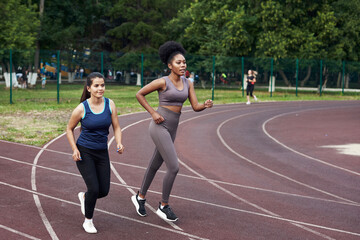 Two young girls go in for sports at the stadium. Jogging in the open air