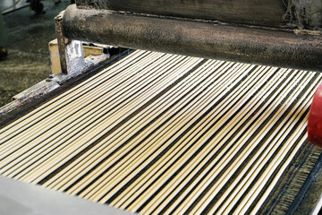 Raw dough for bread sticks on the production line of the bakery. Sprinkled salt on straws on a conveyor. Mechanized bakery industry.