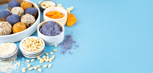 Homemade blue matcha butterfly pea tea powder energy balls in a ceramic bowl on a top view background, healthy sweets made of nuts, dry apricots, sesame. Concept vegeterian diet sweet brain food
