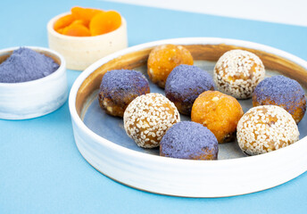 Homemade blue matcha butterfly pea tea powder energy balls in a bowl on a diagonal background, close up, healthy sweets made of nuts, dry apricots, sesame. Concept vegeterian diet sweet brain food