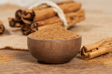 Cinnamon powder and cinnamon stick; photo on wooden background.