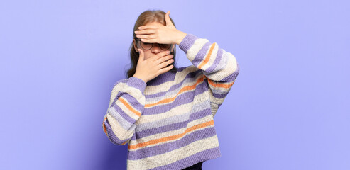 blonde pretty woman covering face with both hands saying no to the camera! refusing pictures or...