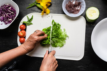 Top view of Chef's hands chopping lettuce on a white board
