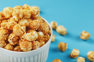 Caramel popcorn in a cup on a blue background, top view.