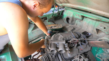 Professional repairer fixing motor of old car in garage. Skillful repairer rebuilding engine on old...