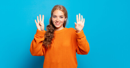 blonde pretty woman smiling and looking friendly, showing number nine or ninth with hand forward,...