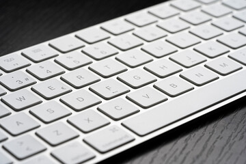 Teclado blanco y de metal sobre mesa de madera negra