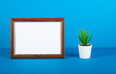 Empty photo frame and flower on table. Blue background.Mock up.