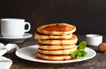 Pancakes with maple syrup and mint on the kitchen table. Breakfast.