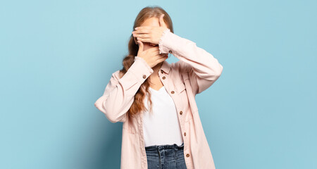 blonde pretty woman covering face with both hands saying no to the camera! refusing pictures or...