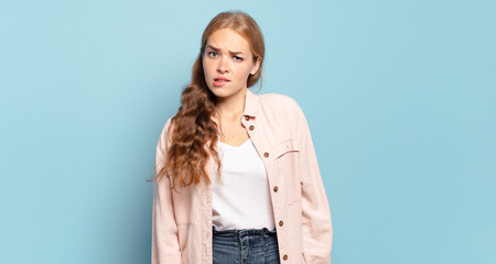 blonde pretty woman feeling clueless, confused and uncertain about which option to pick, trying to...