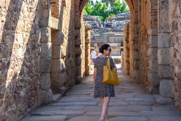 50-year-old white woman with a dress, mustard yellow bag and sunglasses accessing the great Roman amphitheater of Mérida (Spain)