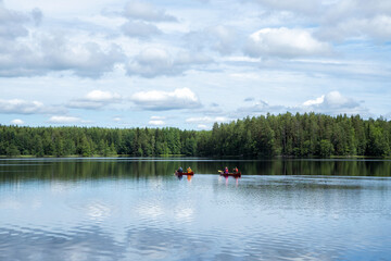People in life vests canoeing in forest lake. Tourists traveling in Finland, having adventure.