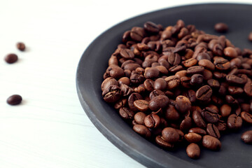 Coffee beans on a black plate, close-up, top view
