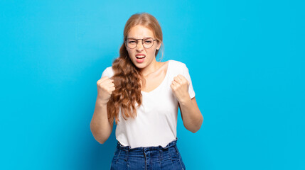 blonde pretty woman shouting aggressively with annoyed, frustrated, angry look and tight fists,...