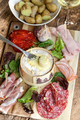 Fromage chaud Mont d'or ou boite chaude accompagné de charcuterie et pommes de terre (spécialité du Jura, france)