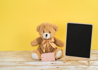 Valentines day teddy bear on white table and blackboard and yellow background