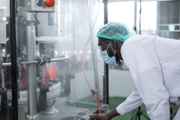 African American black man worker inspecting drink product on bottling factory machinery. Process of beverage industrial concept. 