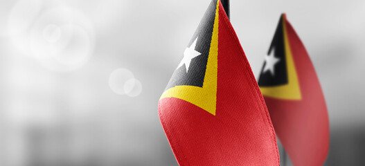 Small national flags of the East Timor on a light blurry background