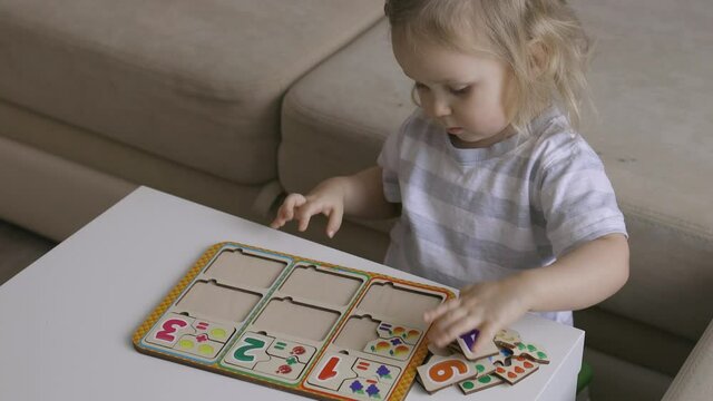 Little girl playing puzzel with numbers on the table. Figures. Handheld close up shot.