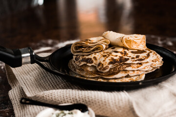 preparation of crepes. A stack of buttered pancakes on a pan. Blurred background. Light rays fall on the table. hot ruddy toasted pancakes on linen towel. Shrovetide or pancake week 