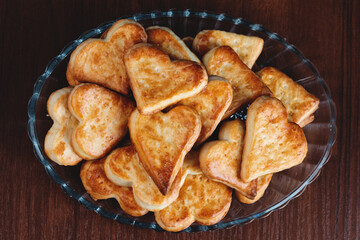 homemade heart shape cookies on a glass plate on a wooden background with film grain effect