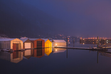 Boathouses reflected on Kootenay Lake on a calm winter's evening in Nelson, B.C., Canada.